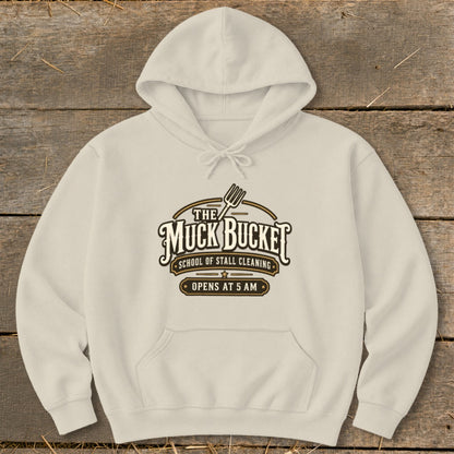 Cream hoodie with "The Muck Bucket School of Stall Cleaning Opens at 5 AM" logo.