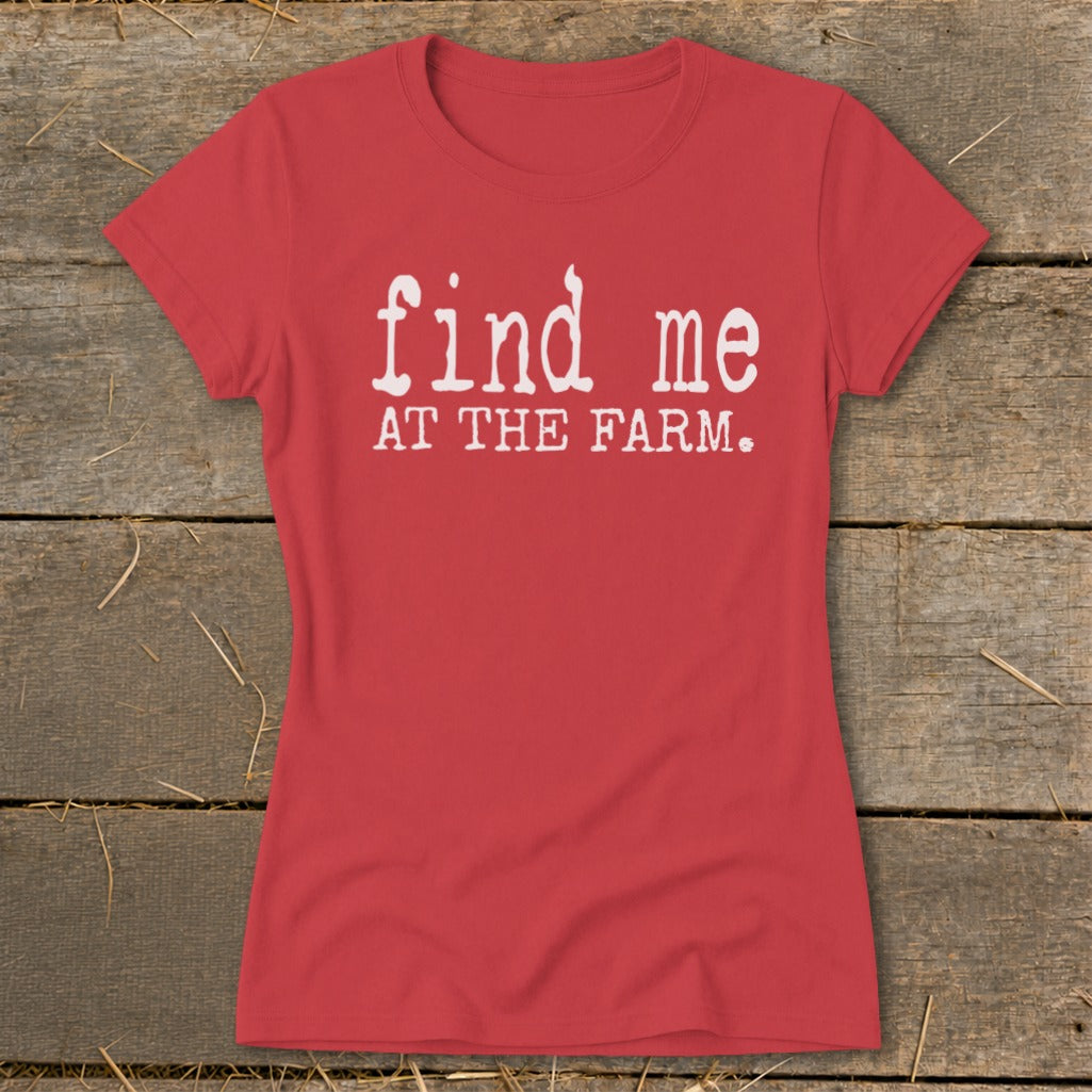 Red t-shirt with white text "find me AT THE FARM." on a wooden background.