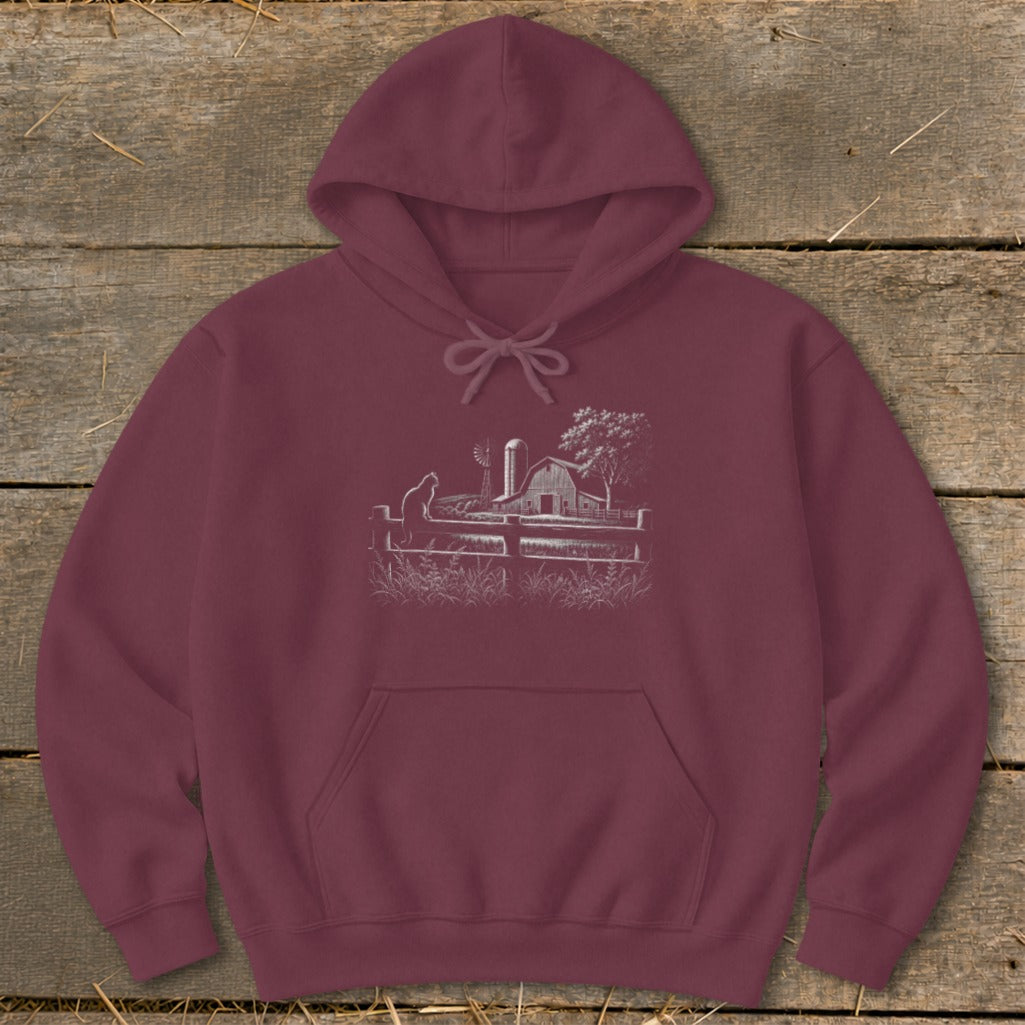Maroon hoodie with a white line drawing of a barn, windmill, and cat on a fence.