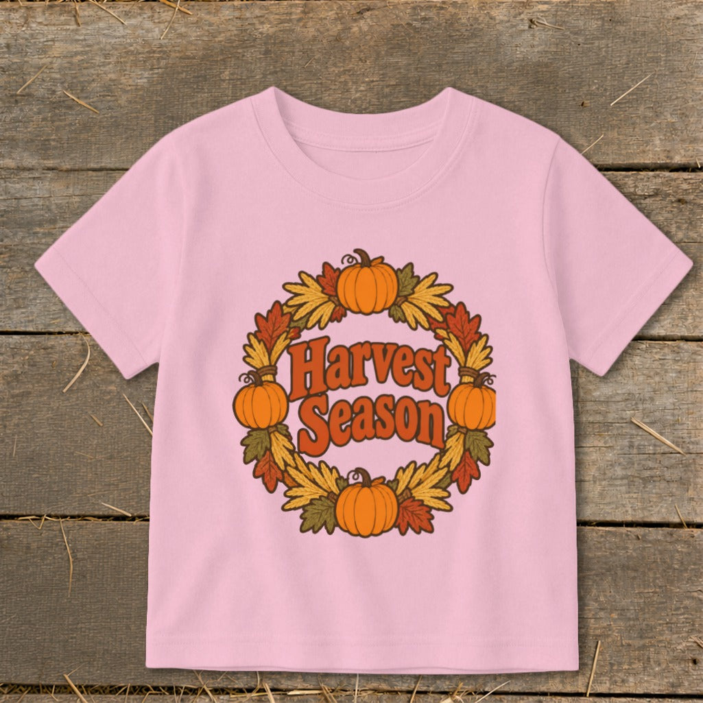 Pink t-shirt with "Harvest Season" text inside a pumpkin and leaf wreath.