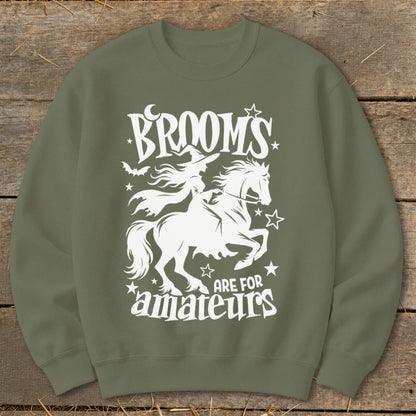 Green sweatshirt with white graphic of a witch on a horse and text "Brooms are for amateurs".