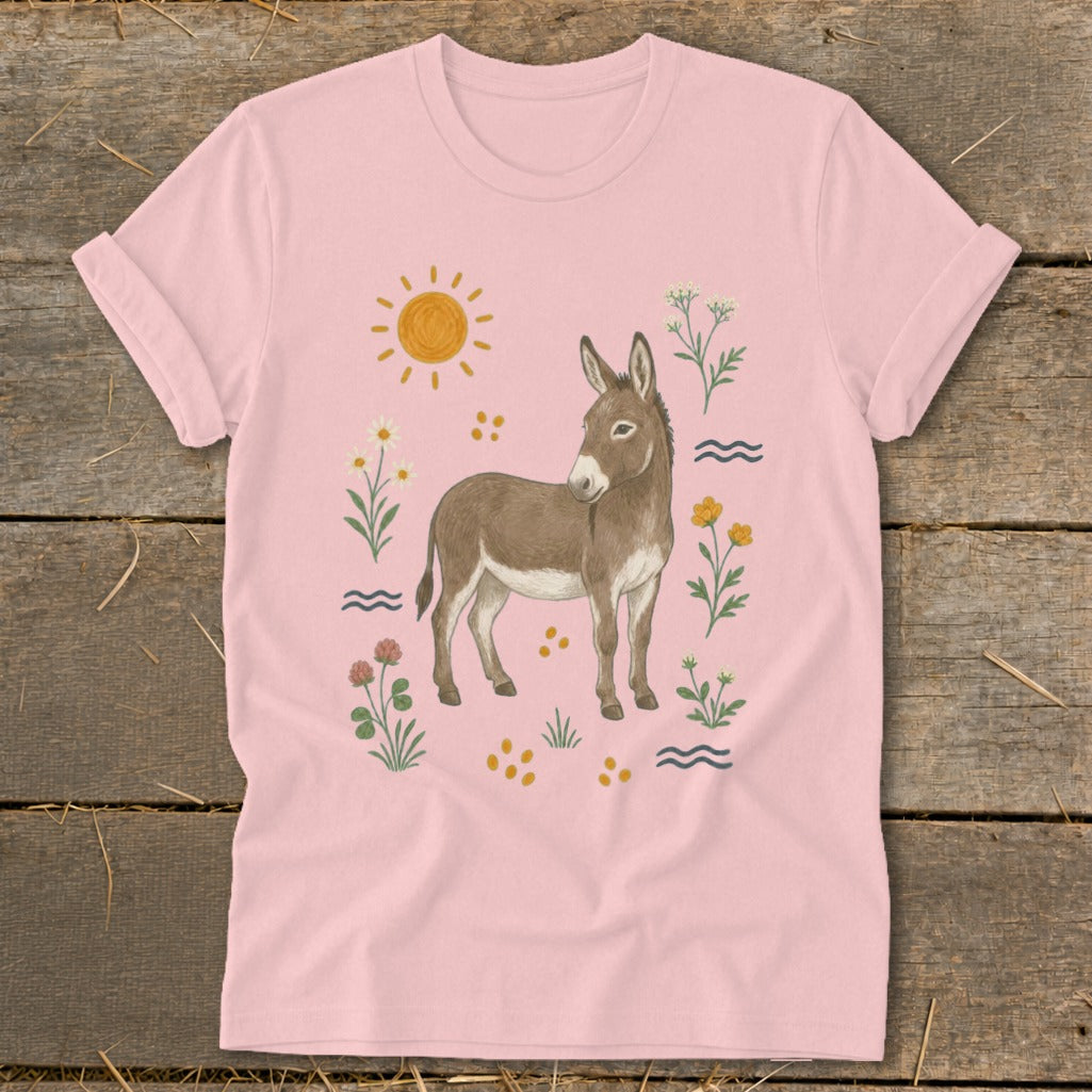 Pink t-shirt with a watercolor illustration of a donkey surrounded by flowers and sun.