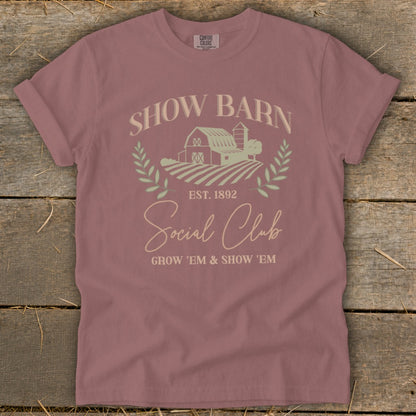Show Barn Social Club graphic on a mauve t-shirt with farm imagery and text.