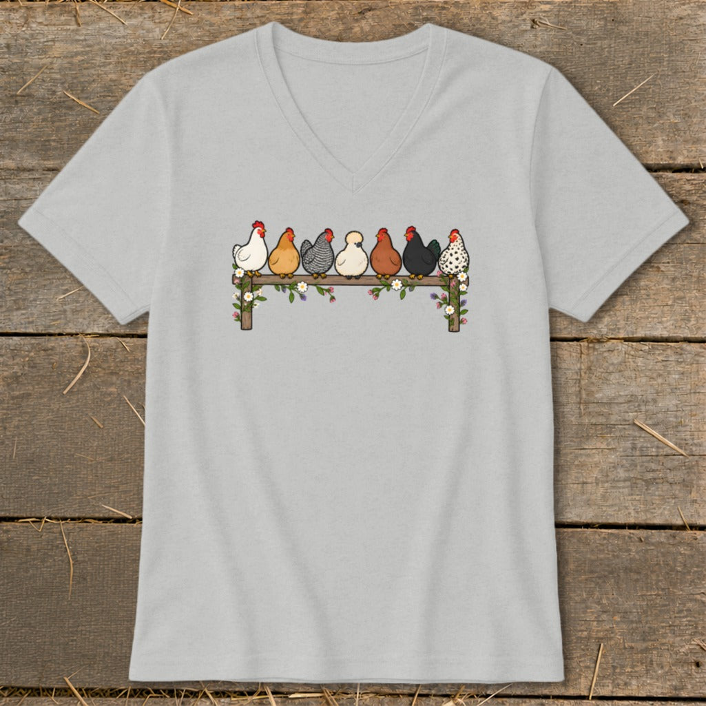 Light gray V-neck t-shirt featuring an illustration of seven colorful chickens perched on a flower-covered fence.