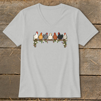 Light gray V-neck t-shirt featuring an illustration of seven colorful chickens perched on a flower-covered fence.