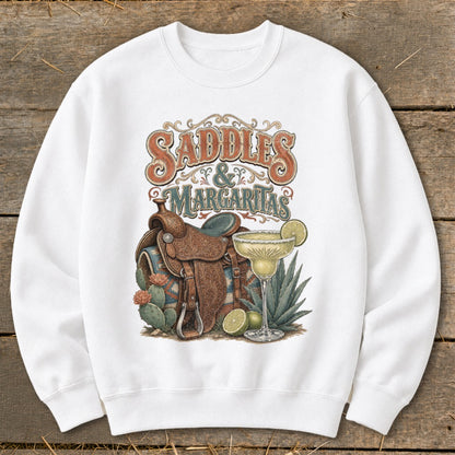 White sweatshirt with "Saddles & Margaritas" text, saddle, margarita, and cacti graphic.