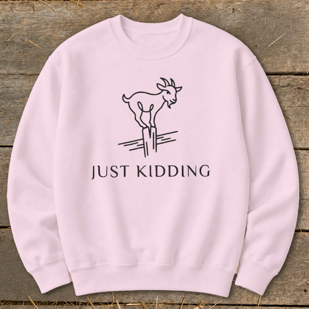 Pink sweatshirt with line drawing of a goat and "JUST KIDDING" text.