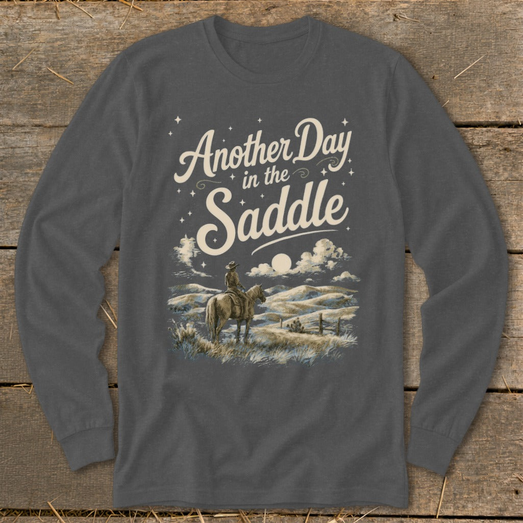 Long sleeve shirt with "Another Day in the Saddle" text and cowboy on horseback at dusk.