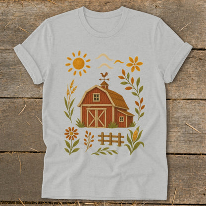 Light gray t-shirt with a farm scene graphic: red barn, sun, flowers, wheat, fence, and corn.