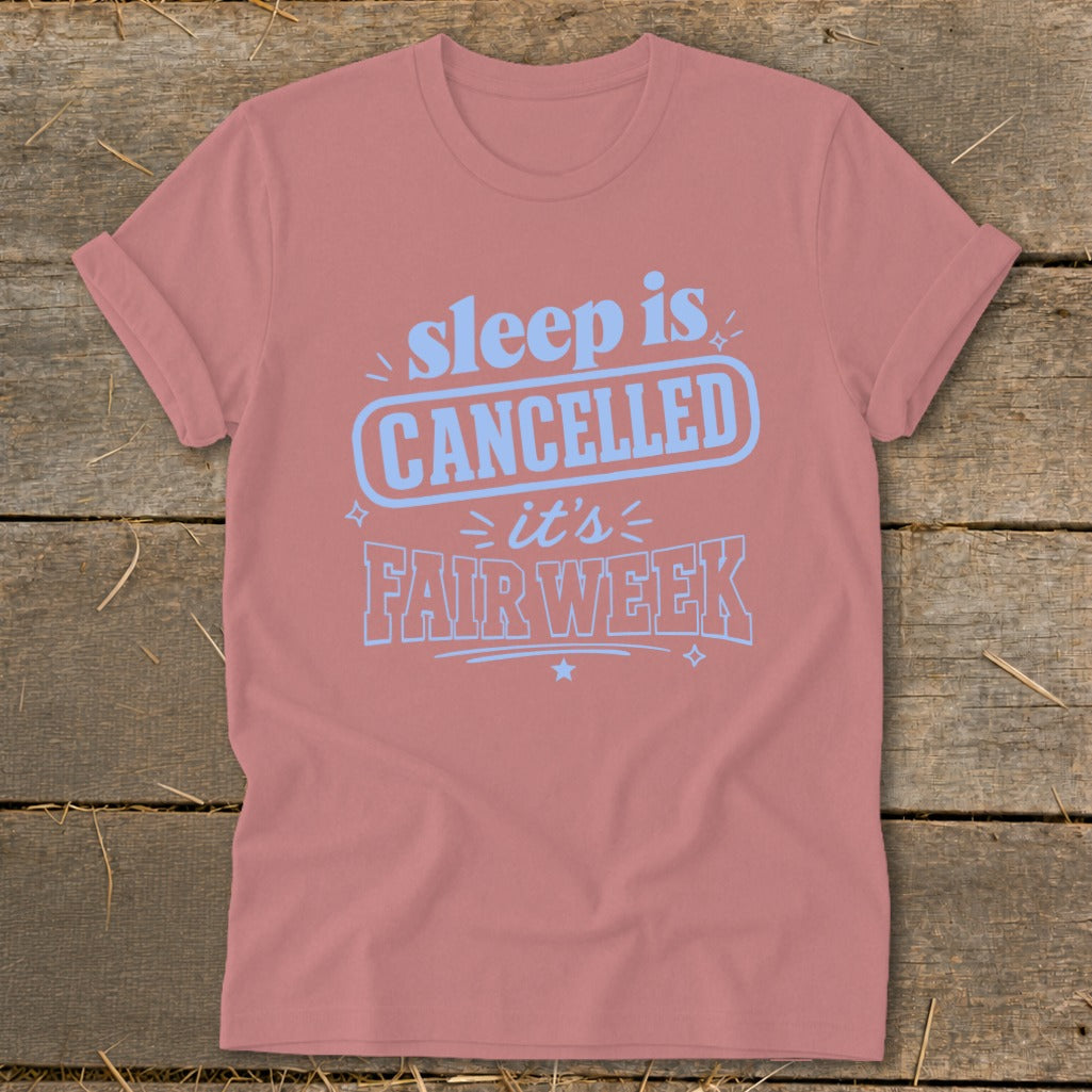 Pink t-shirt with light blue text that says "sleep is CANCELLED it's FAIR WEEK".