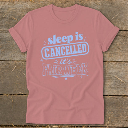 Pink t-shirt with light blue text that says "sleep is CANCELLED it's FAIR WEEK".