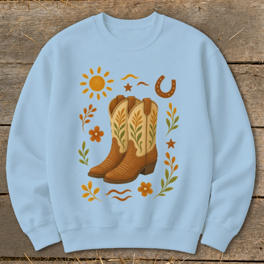 Light blue sweatshirt with a Western-themed graphic featuring cowboy boots, sun, horseshoe, and floral accents.