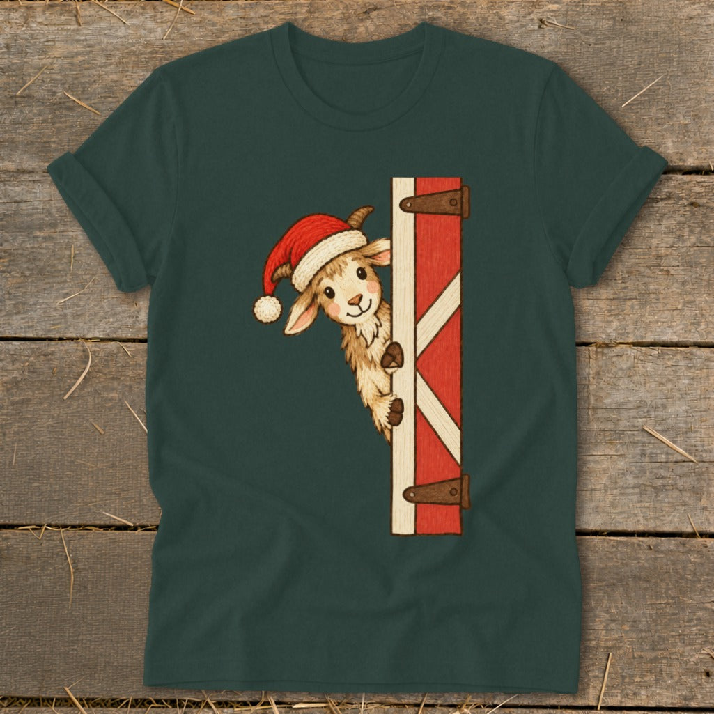 Goat wearing Santa hat peeking from behind barn door on a green t-shirt.