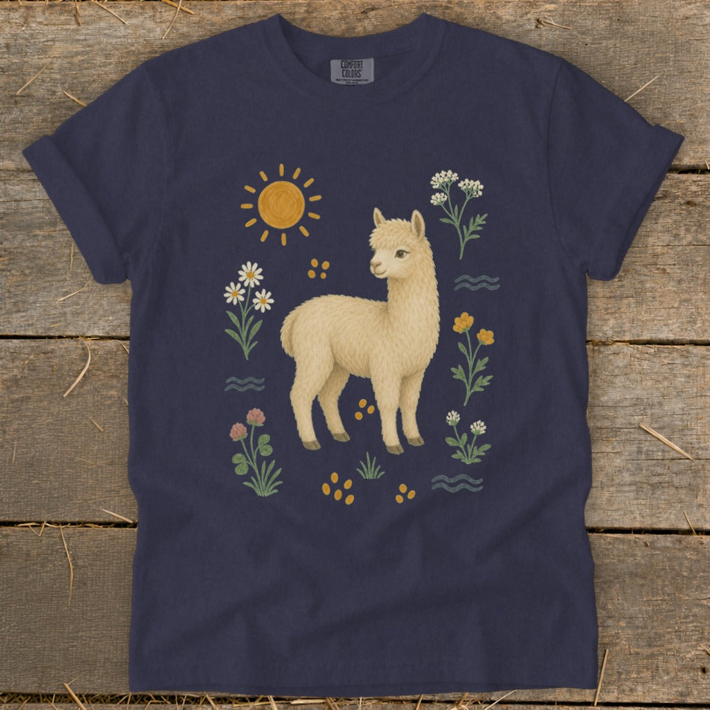 Navy t-shirt with a light brown alpaca surrounded by flowers, sun, and decorative elements.