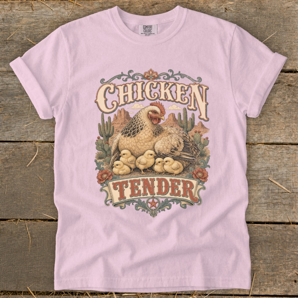 Pink t-shirt graphic with "Chicken Tender" text and hen with chicks in desert scene.