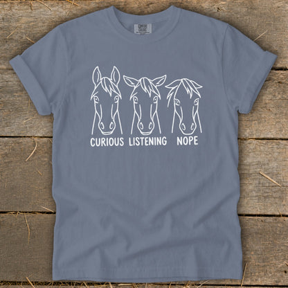 A grey short-sleeved t-shirt with three horse head line drawings and text reading CURIOUS, LISTENING, NOPE.