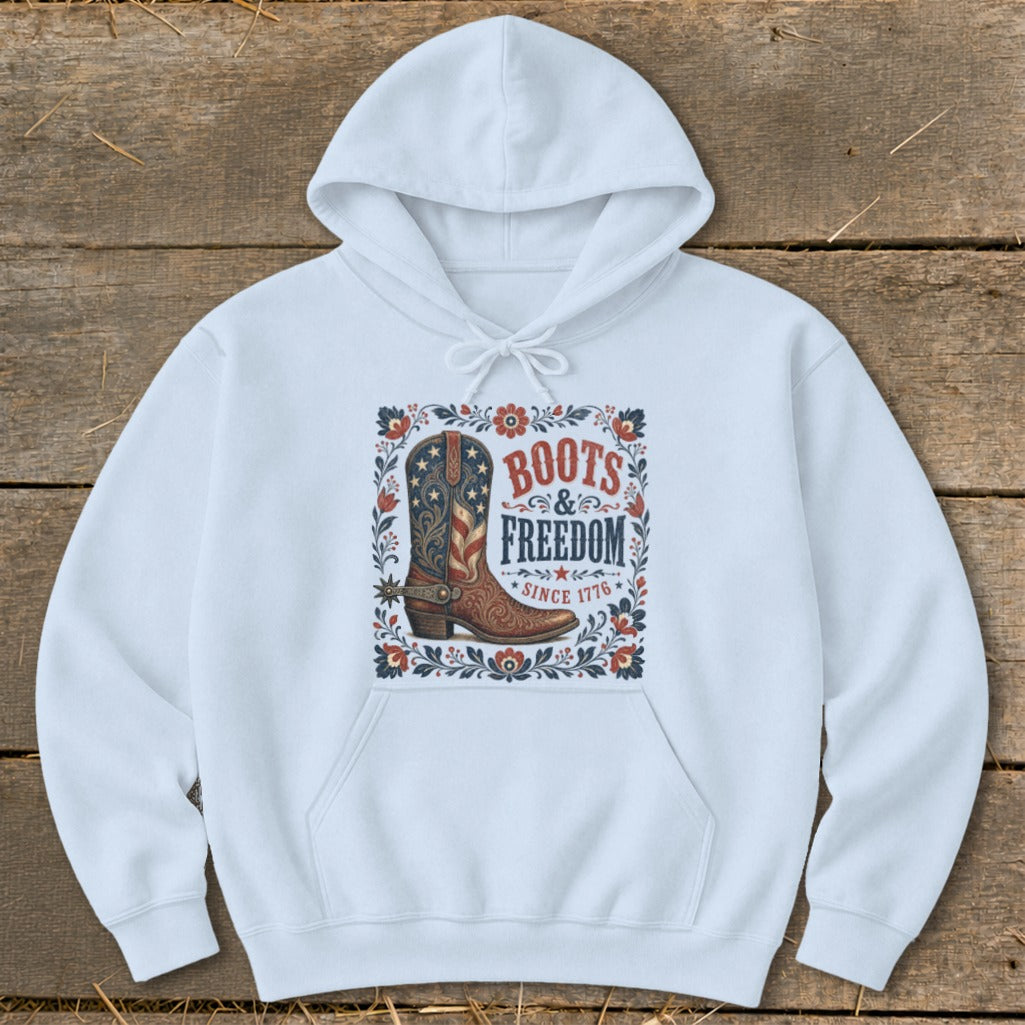 White hoodie with a graphic of a patriotic cowboy boot and text "Boots & Freedom Since 1776".