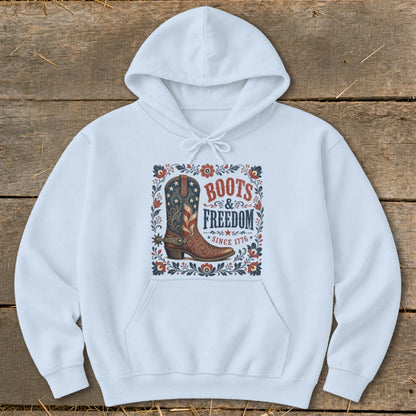 White hoodie with a graphic of a patriotic cowboy boot and text "Boots & Freedom Since 1776".