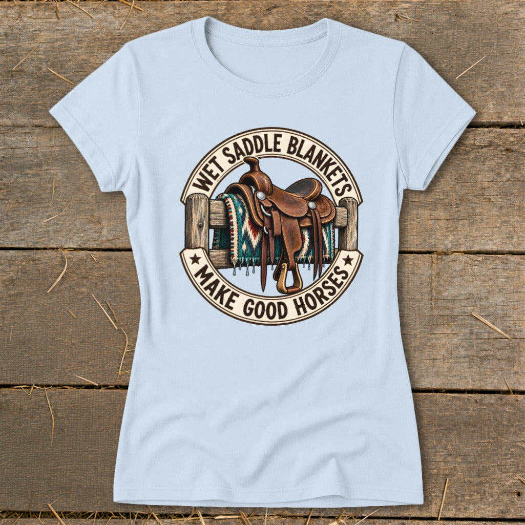 Light blue t-shirt with a circular graphic featuring a saddle on a fence and the text "WET SADDLE BLANKETS MAKE GOOD HORSES".
