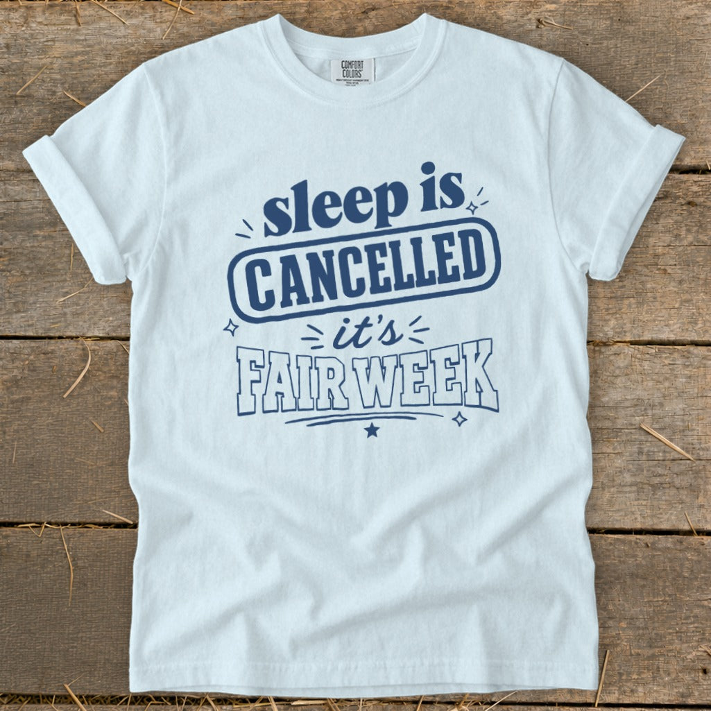 White t-shirt with blue text that reads "sleep is CANCELLED it's FAIR WEEK".