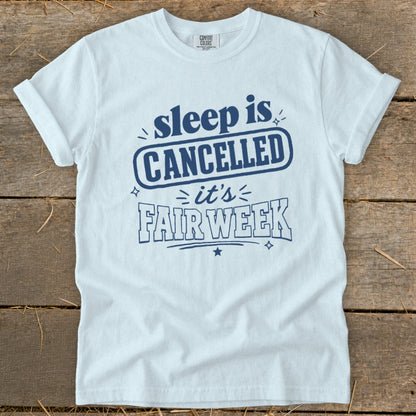 White t-shirt with blue text that reads "sleep is CANCELLED it's FAIR WEEK".
