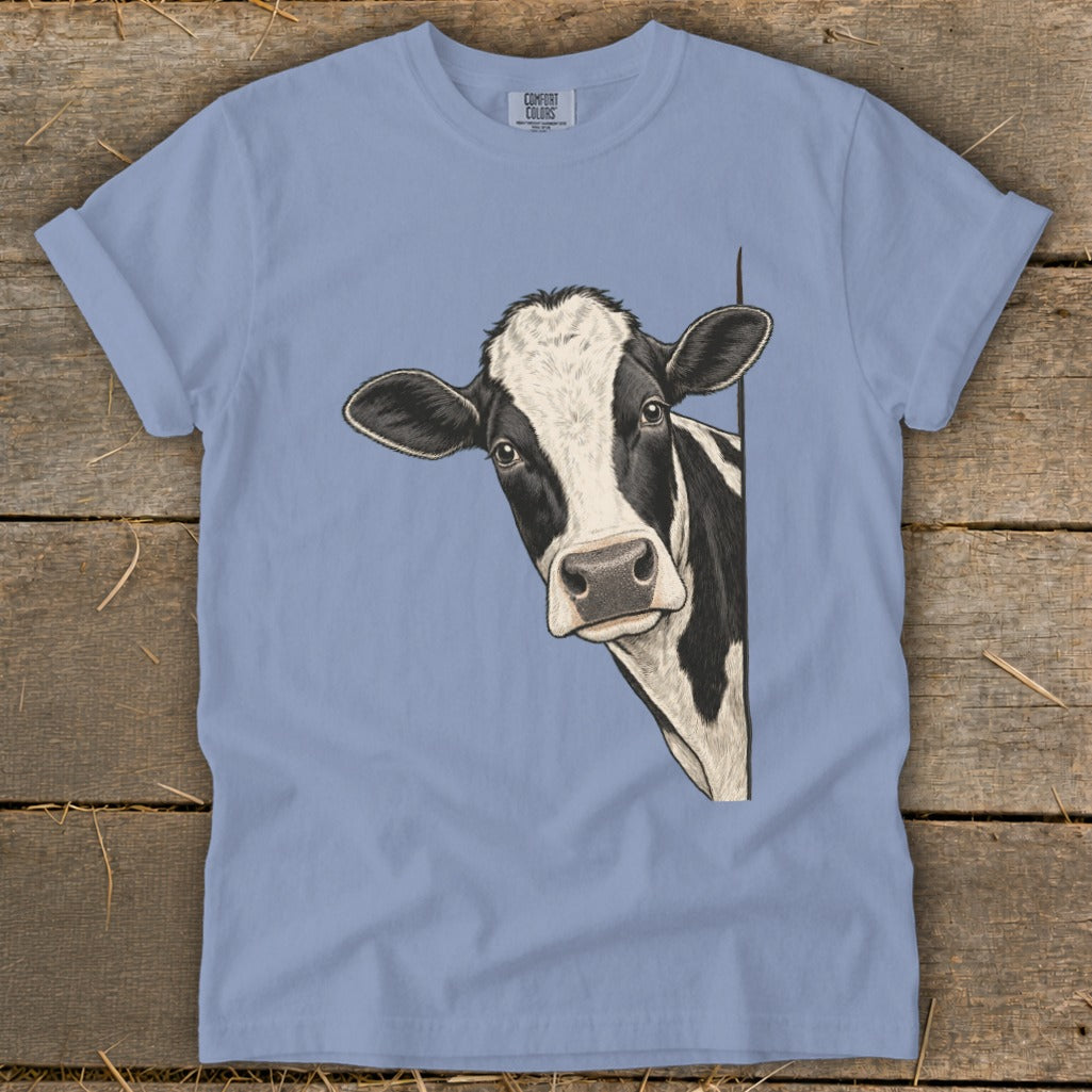 Black and white cow peeking around corner on a light blue t-shirt.