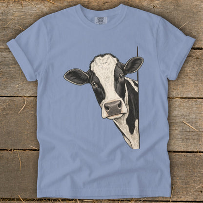 Black and white cow peeking around corner on a light blue t-shirt.