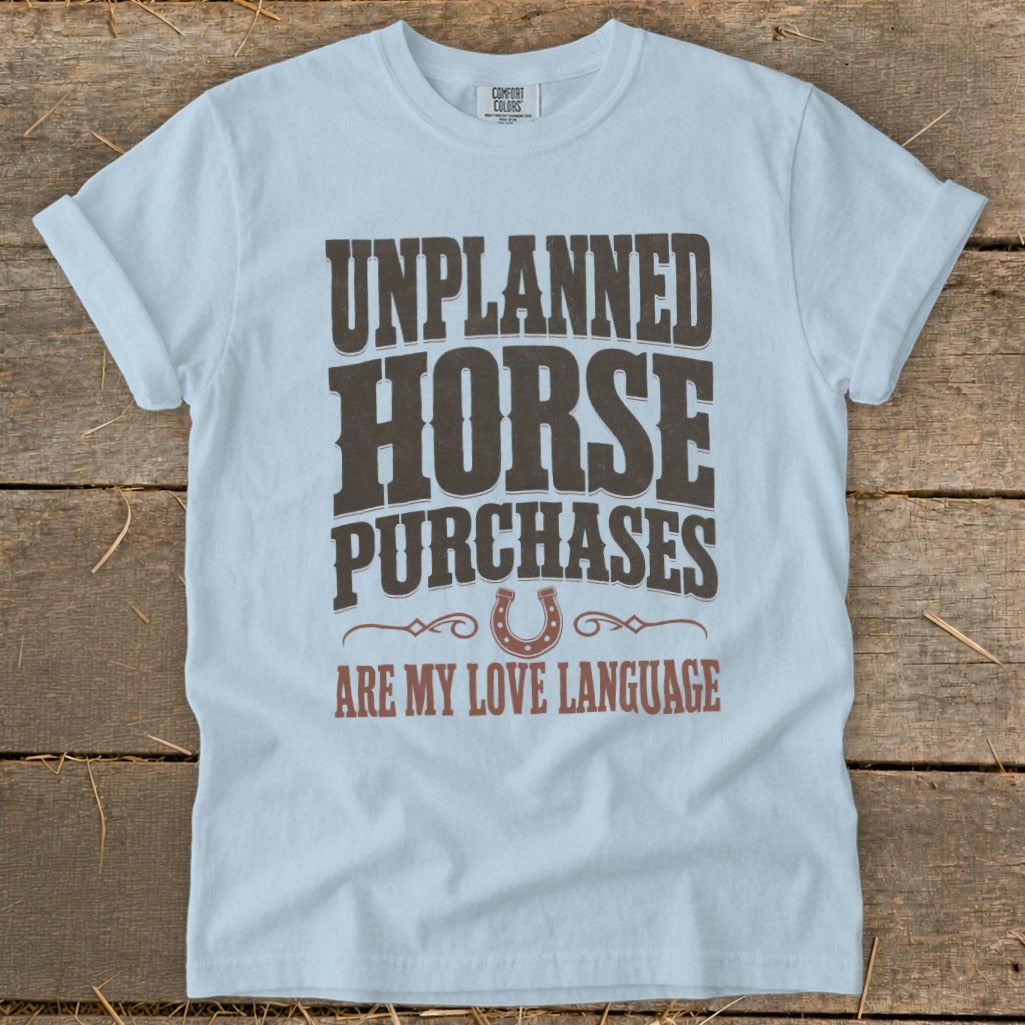 Light blue t-shirt with "Unplanned Horse Purchases Are My Love Language" text and horseshoe graphic.