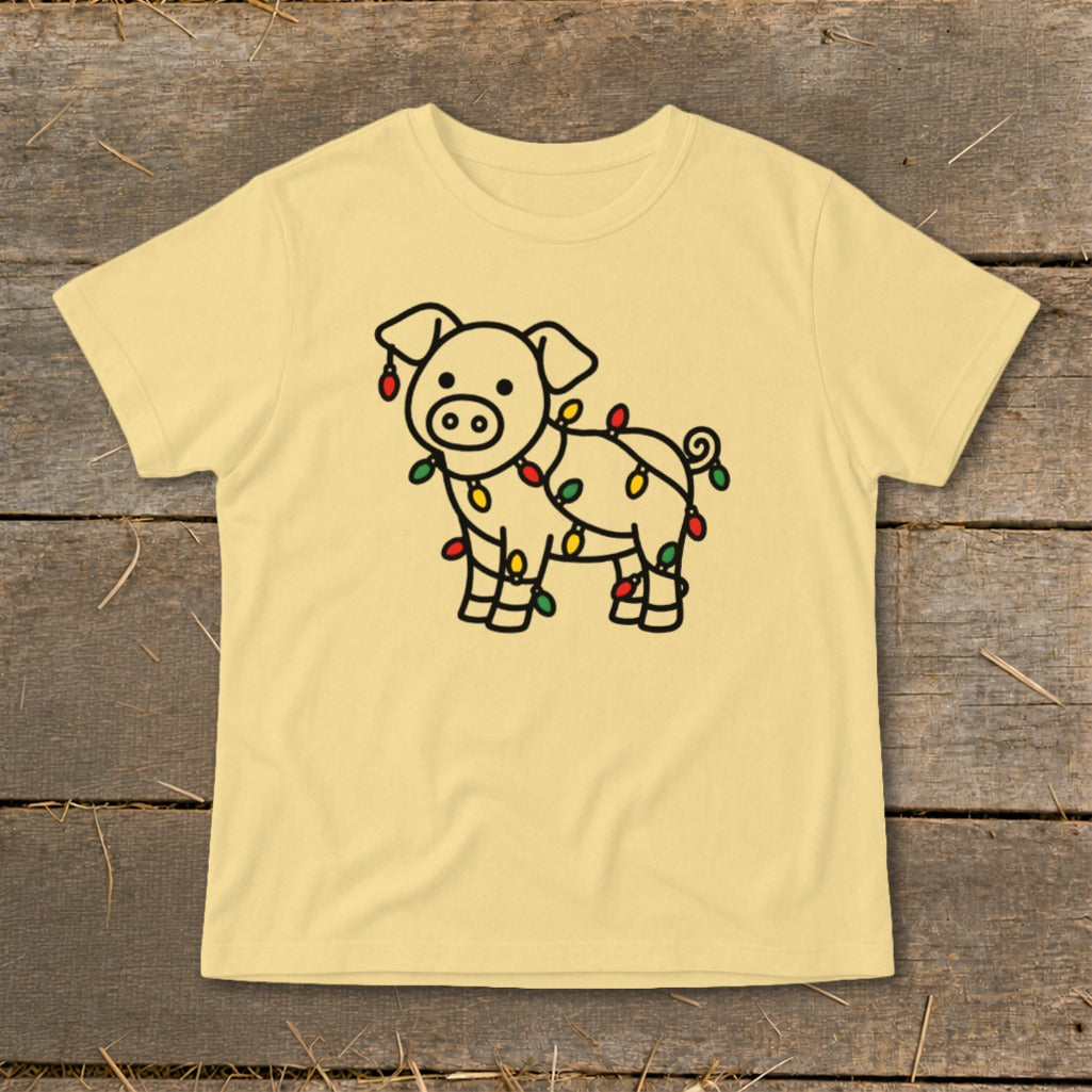 A light yellow short-sleeved t-shirt features a black line drawing of a pig wrapped in Christmas lights.