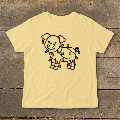 A light yellow short-sleeved t-shirt features a black line drawing of a pig wrapped in Christmas lights.