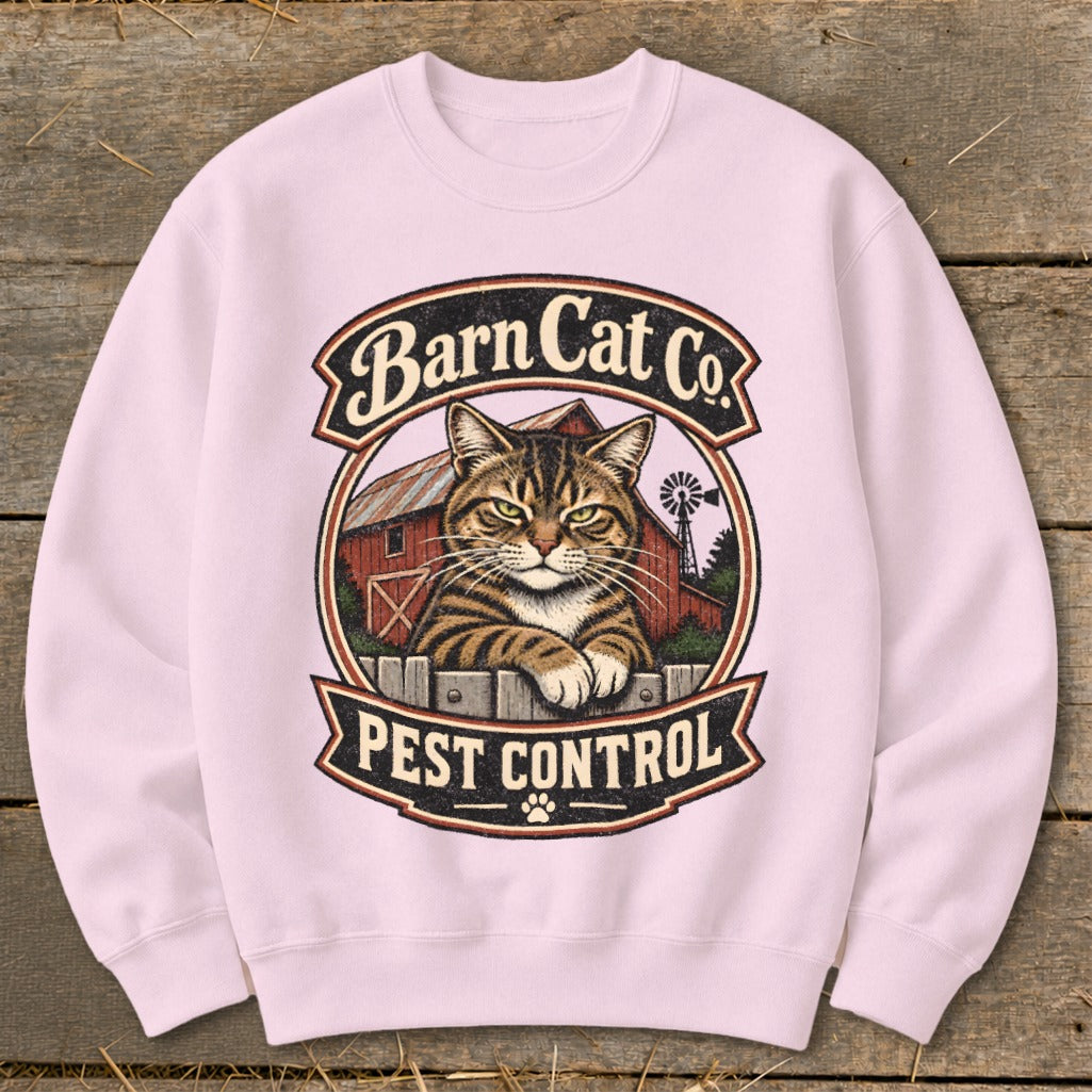 Light pink crewneck sweatshirt featuring a vintage graphic of a tabby cat resting on a fence in front of a red barn, with the text Barn Cat Co. Pest Control.