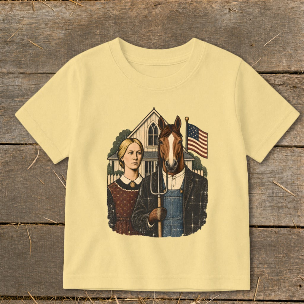 A light yellow short-sleeved t-shirt featuring an illustration of an American Gothic style couple with a horse head holding a pitchfork.