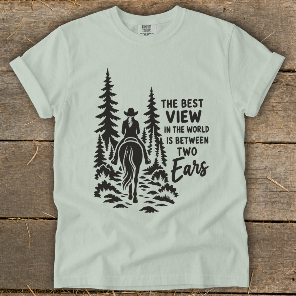Light green t-shirt with a graphic of a horse rider in trees and text.