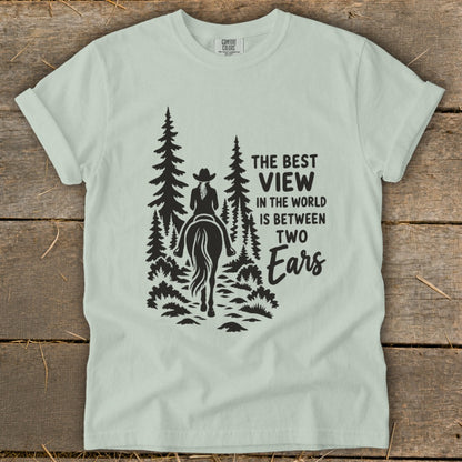 Light green t-shirt with a graphic of a horse rider in trees and text.