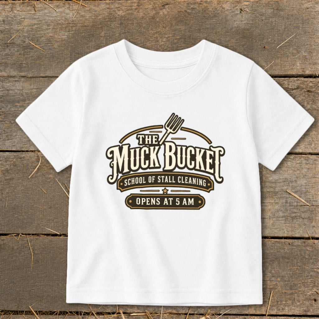 White t-shirt with "The Muck Bucket School of Stall Cleaning Opens at 5 AM" graphic.