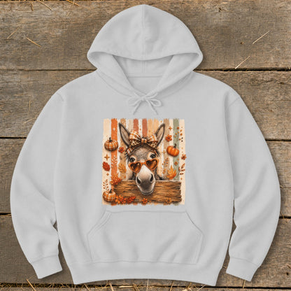 Donkey wearing heart sunglasses and bow, with pumpkins and fall leaves.