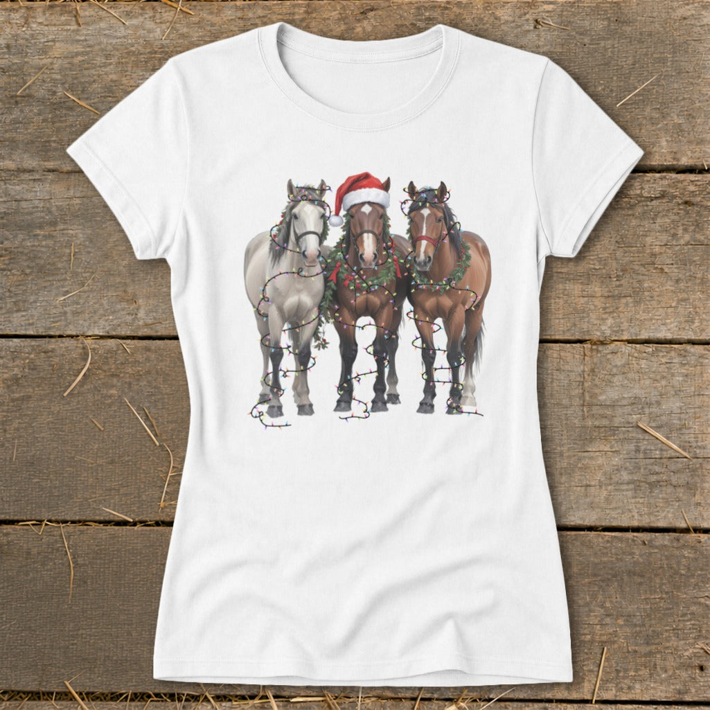 Three horses wearing Christmas lights and one horse wearing a Santa hat.