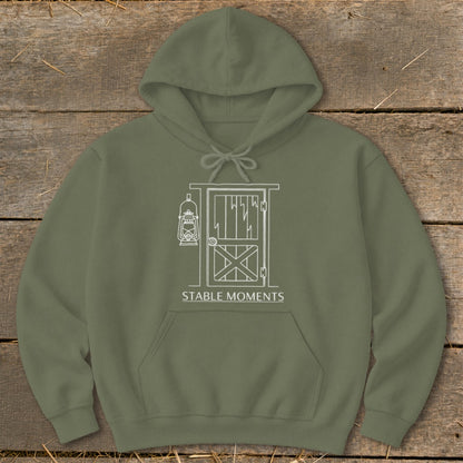 Olive green hoodie with white line art of a barn door and lantern, text says "STABLE MOMENTS".