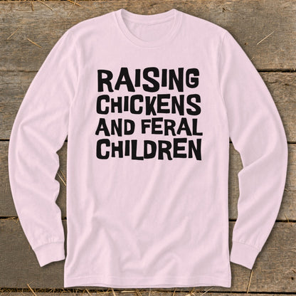 Pink long-sleeve shirt with black text: "RAISING CHICKENS AND FERAL CHILDREN"