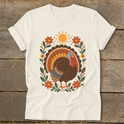 Cream t-shirt with a colorful turkey illustration surrounded by flowers and a sun.