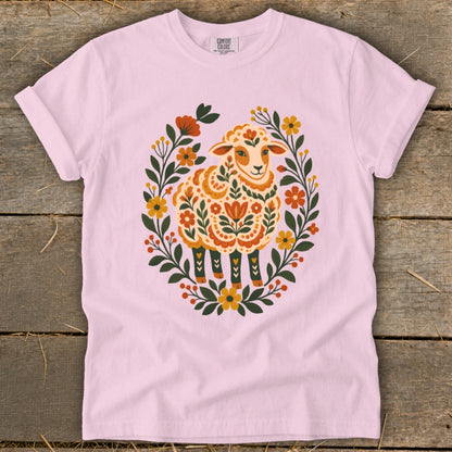 Pink t-shirt with a folk art sheep design framed by flowers and leaves.