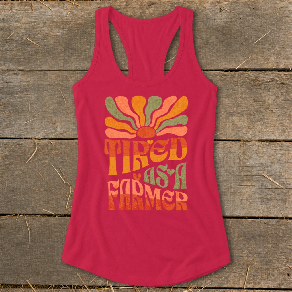 Pink racerback tank top with "Tired as a Farmer" text and colorful sun graphic.