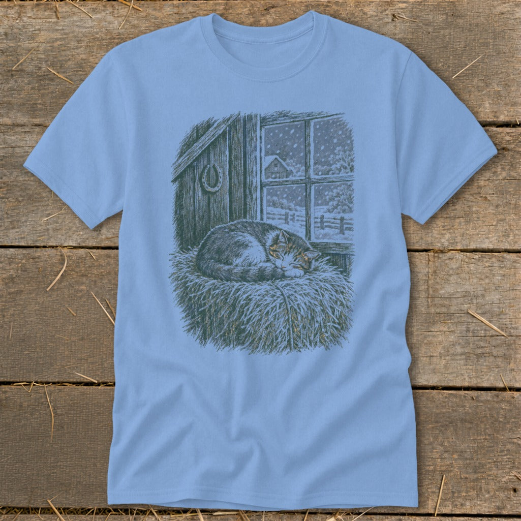 T-shirt with vintage illustration of a cat sleeping on hay in front of a snowy window.