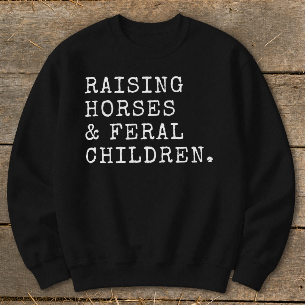 Black sweatshirt with white text: "RAISING HORSES & FERAL CHILDREN."