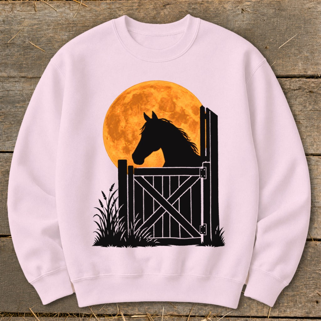Light pink crewneck sweatshirt featuring a graphic of a horse silhouette looking over a stable door against a large orange moon.