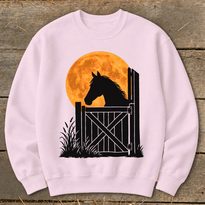 Light pink crewneck sweatshirt featuring a graphic of a horse silhouette looking over a stable door against a large orange moon.
