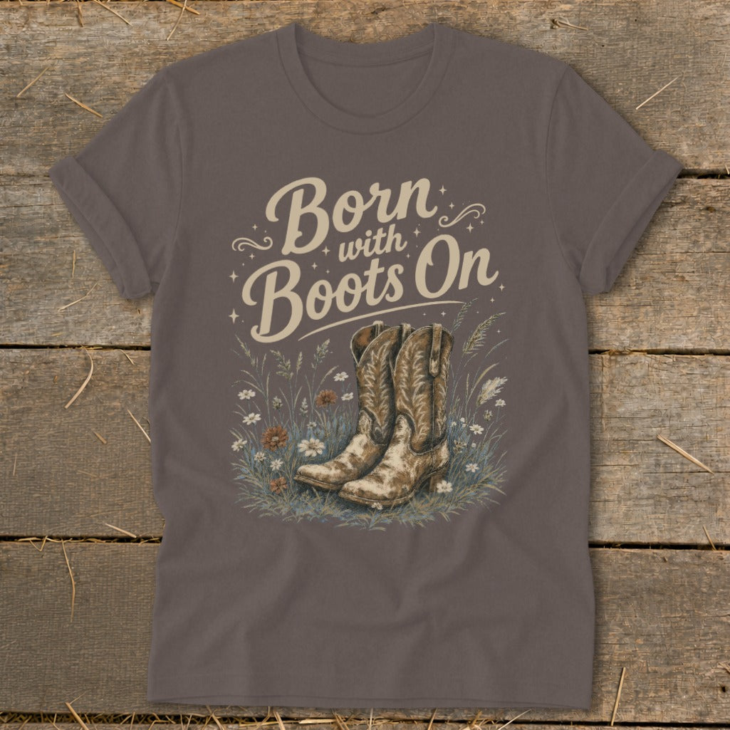 Brown t-shirt with "Born with Boots On" text and cowboy boots in wildflowers.