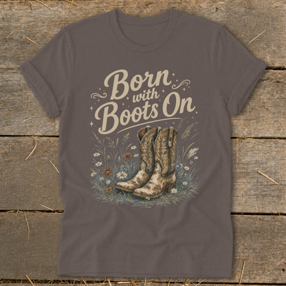 Brown t-shirt with "Born with Boots On" text and cowboy boots in wildflowers.