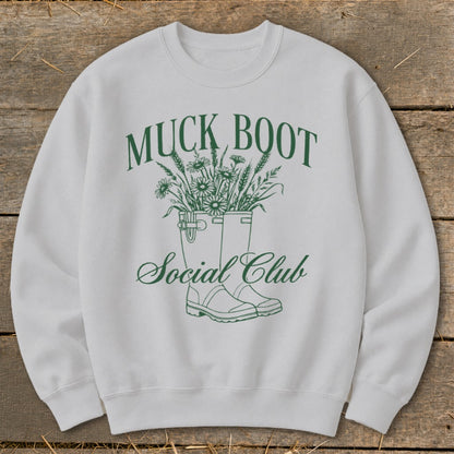 White sweatshirt with green "MUCK BOOT Social Club" text and graphic.