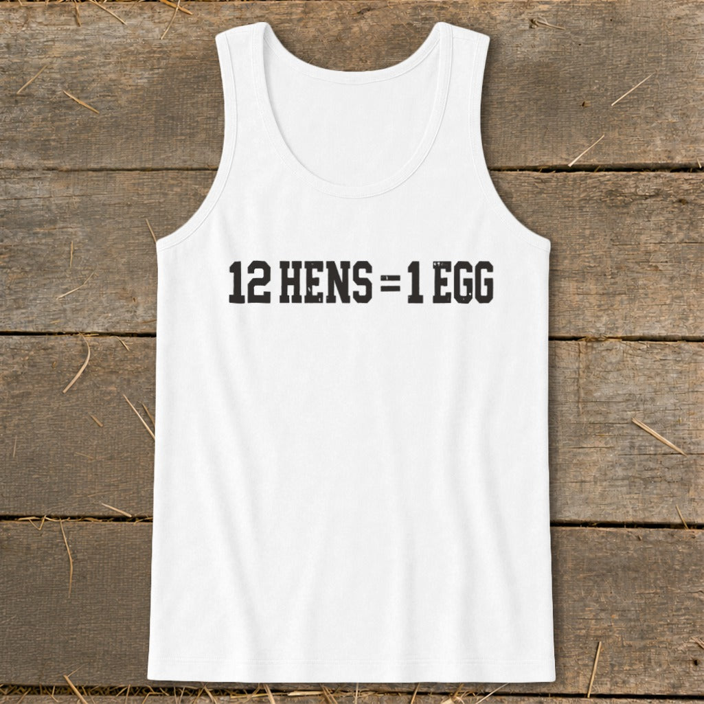 A white tank top with black distressed text reading 12 HENS = 1 EGG, laid flat on a wooden surface.